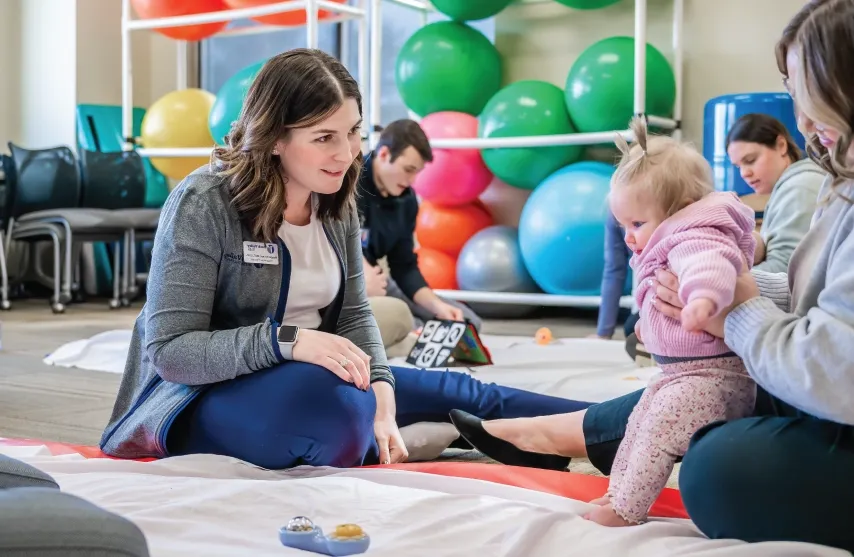 Two women sitting with a baby on the floor.