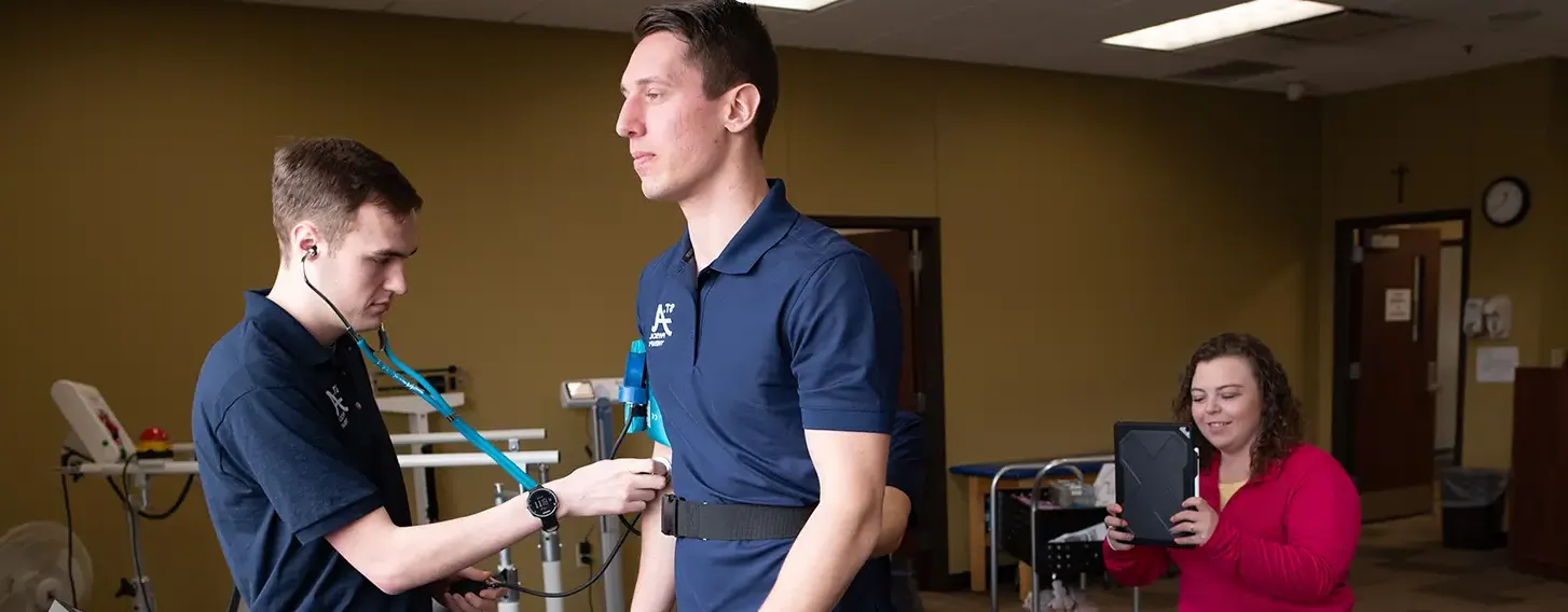 A man on a treadmill being monitored by students in a musculoskeletal lab.